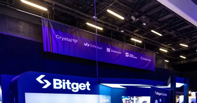 Bitget’s booth at a trade event, with the lit Bitget logo above a display wall.