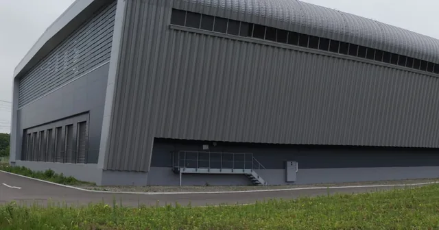Sakura Internet’s Ishikari data centre in Hokkaido: a long grey building with a curved roof, beside a lawn.